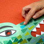 Hand interacting with a colorful paper crocodile mask on an orange background