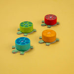 Londji four colorful turtle-shaped wooden pieces on a yellow background