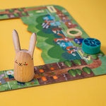 Londji wooden rabbit figure on a colorful board game with a yellow background