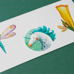 Londji colorful temporary tattoos of a dragonfly, unicorn, and flower on a white card against a green background.