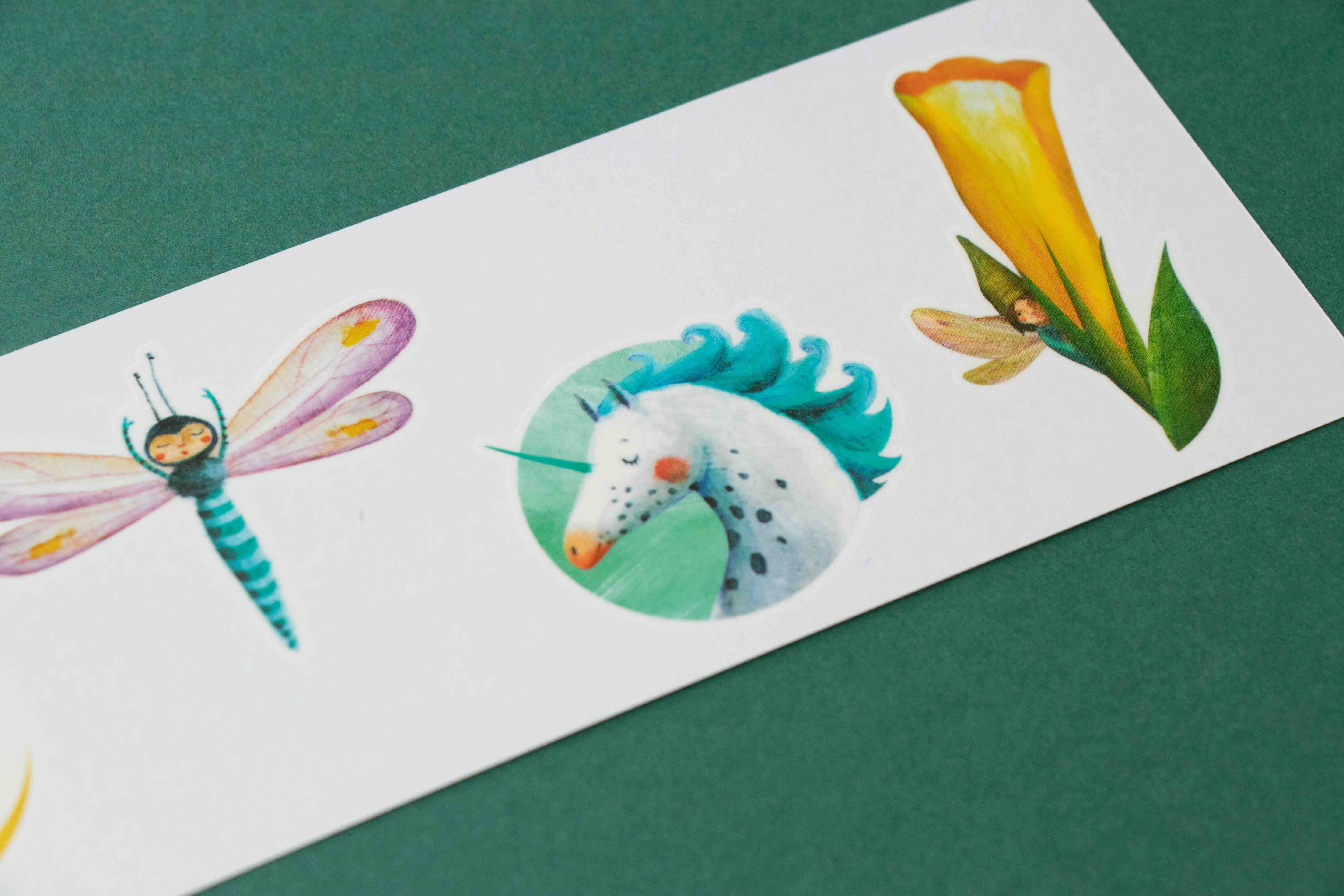 Londji colorful temporary tattoos of a dragonfly, unicorn, and flower on a white card against a green background.