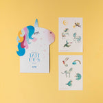 Londji unicorn-shaped card with small tattoo designs on a yellow background