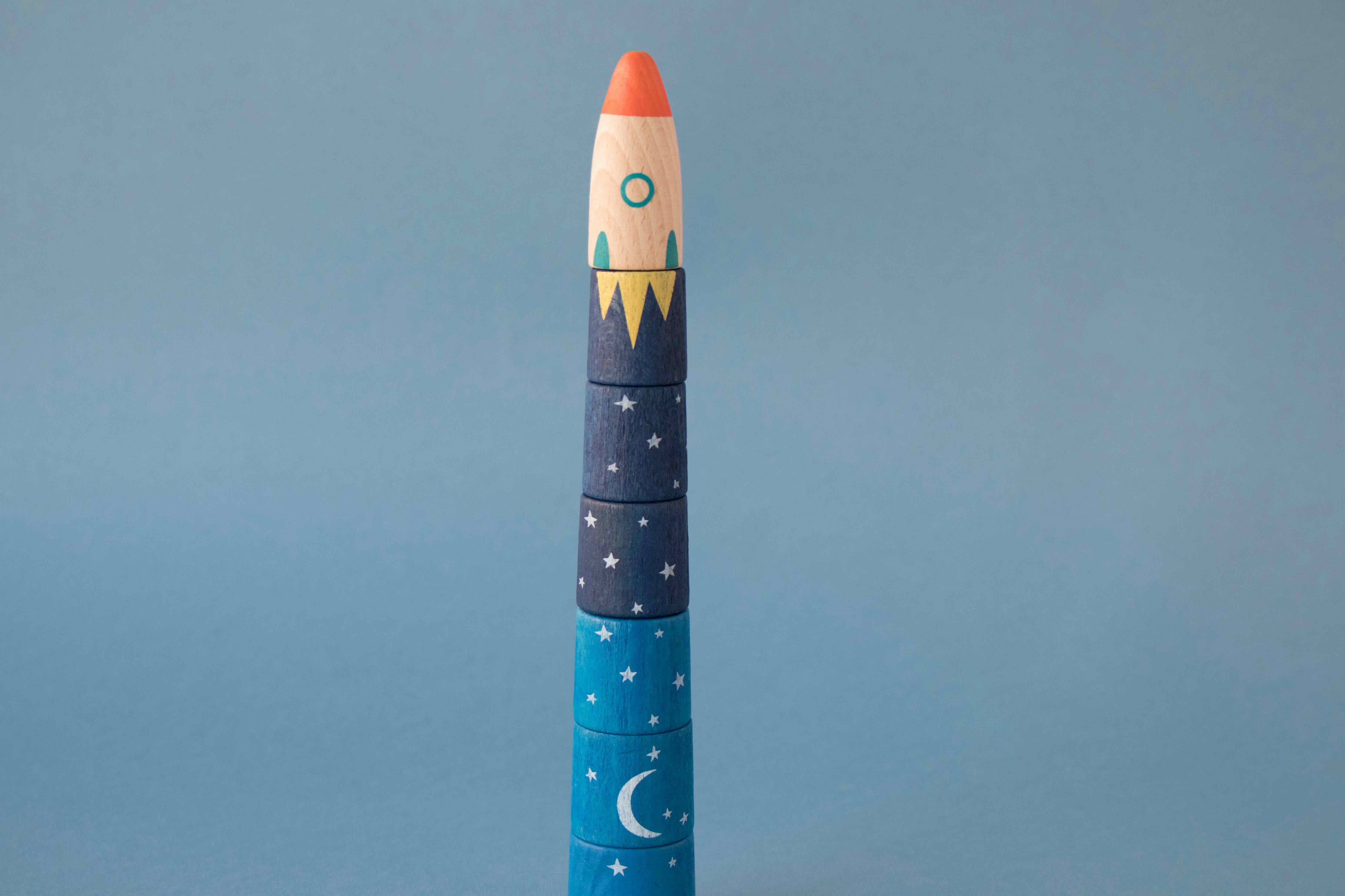 Londji toy rocket shaped with a blue body and red top on a gray background