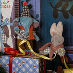 Two toy animals, an elephant and a rabbit, sitting on a decorative setup with a gift box and ribbon.