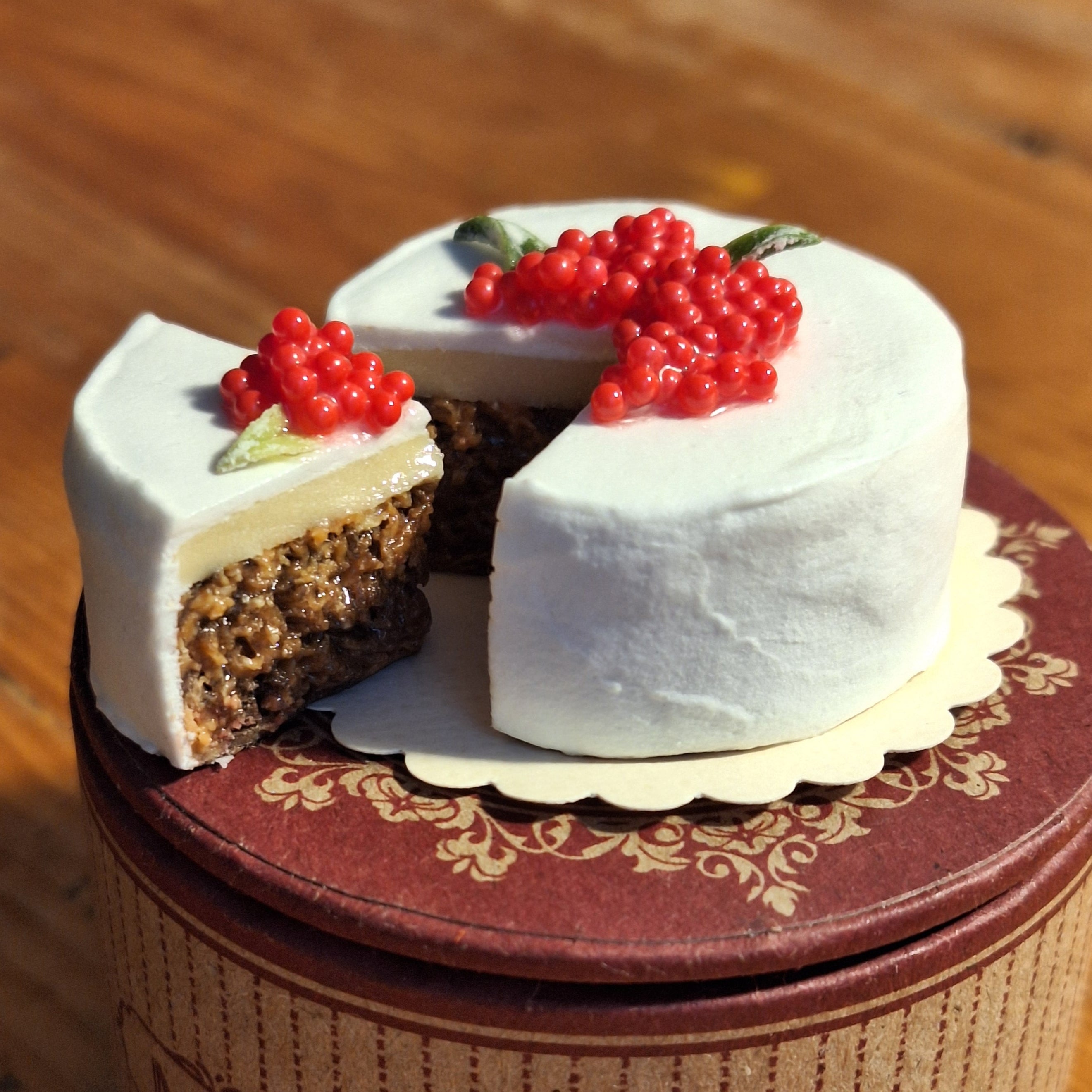 Small cake with white frosting and red berries on a decorative stand.