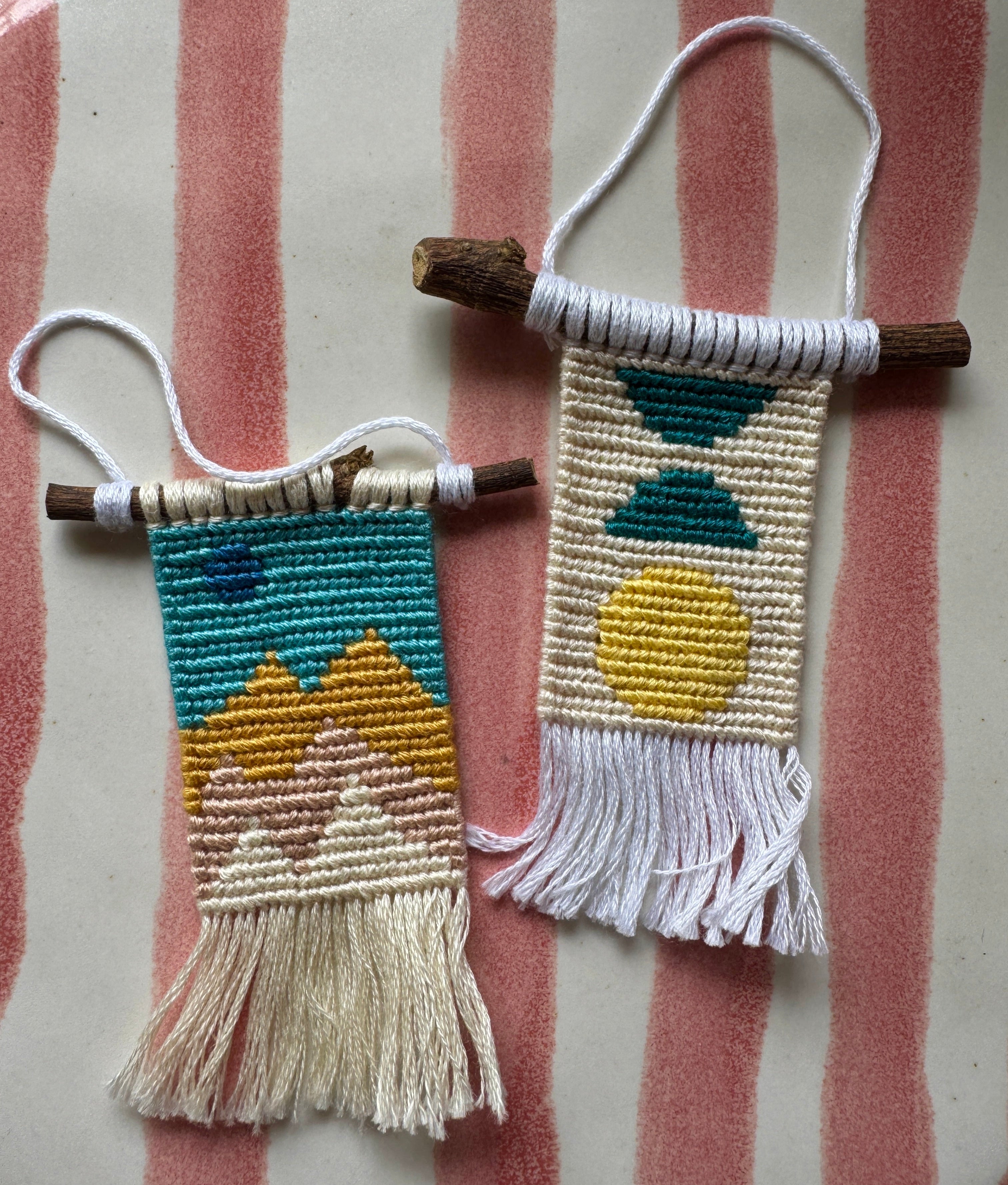 Two small woven wall hangings with colorful patterns on a striped fabric background.