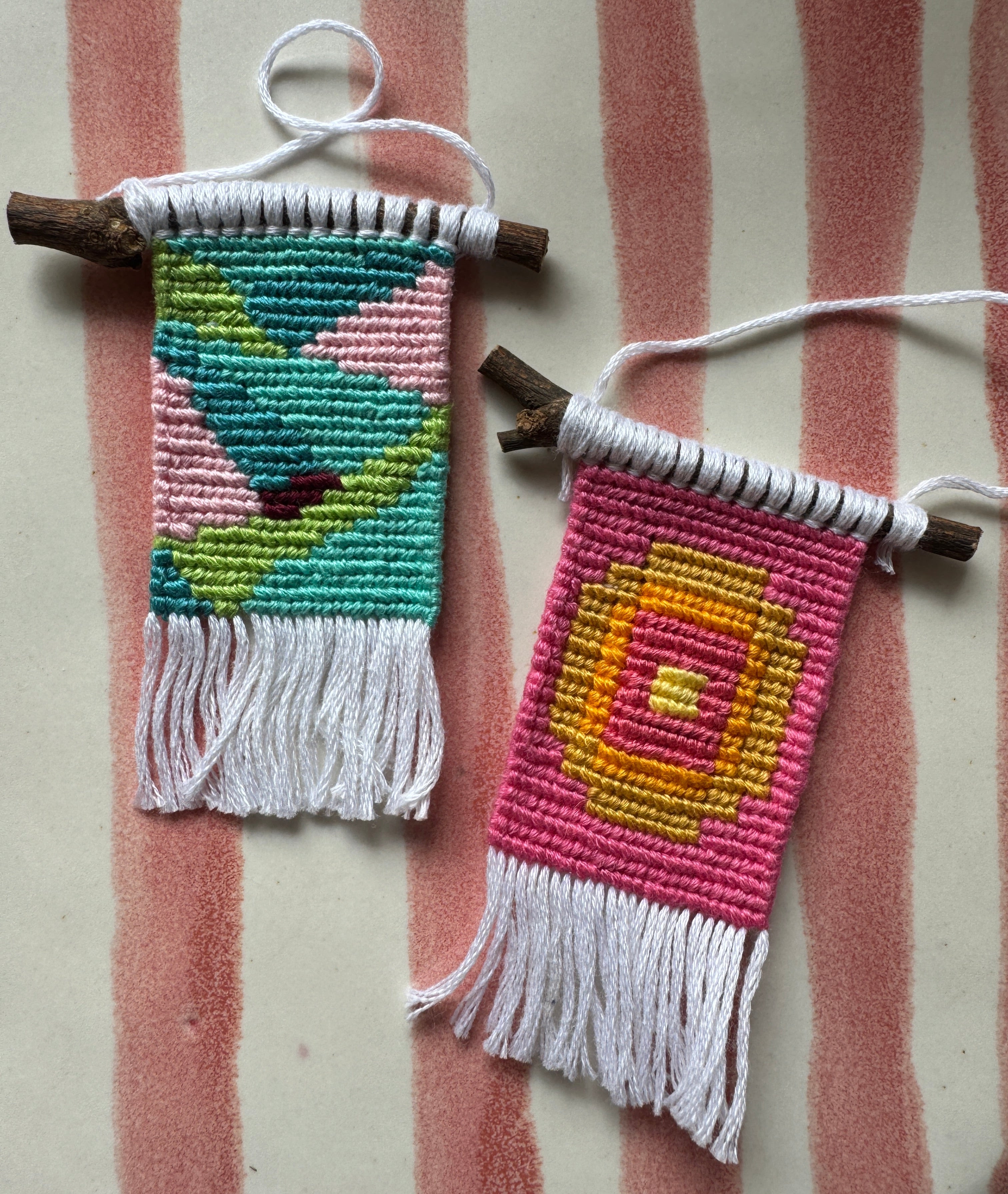 Two small woven pouches with colorful patterns on a striped fabric background
