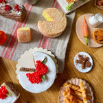Various small food items and pastries on a wooden table with a checkered cloth.