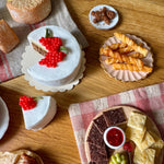 Assorted pastries and desserts on a wooden table with a checkered cloth.