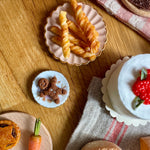 Assorted pastries and bread on a wooden table with a checkered cloth.