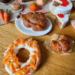 Assorted baked goods including cakes, pastries, and a roasted chicken on a wooden table.