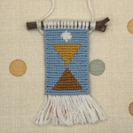 Decorative woven wall hanging with geometric design on a polka dot background