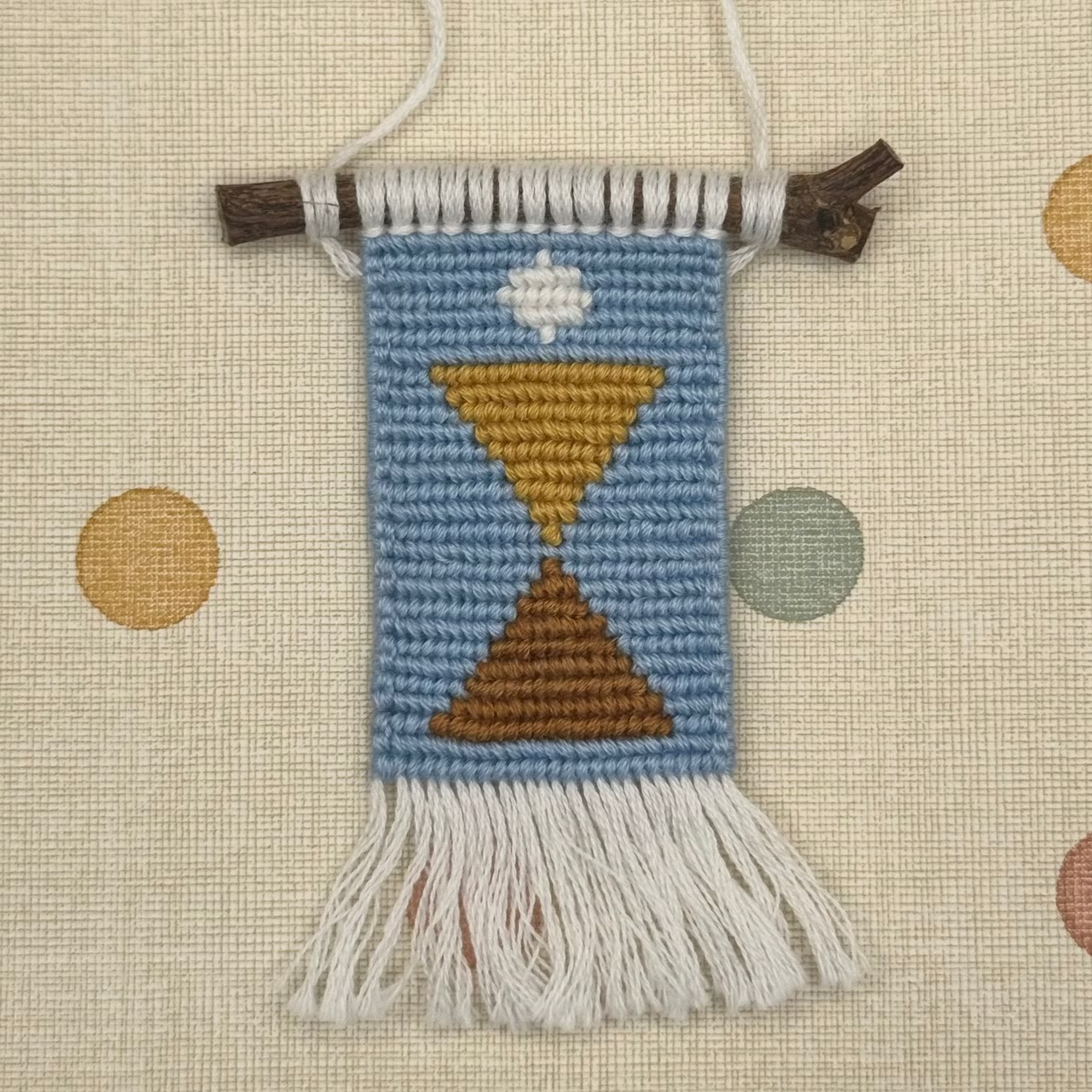 Decorative woven wall hanging with geometric design on a polka dot background