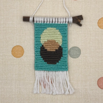 Textile art piece with a portrait of a person with a green background on a polka dot fabric background.