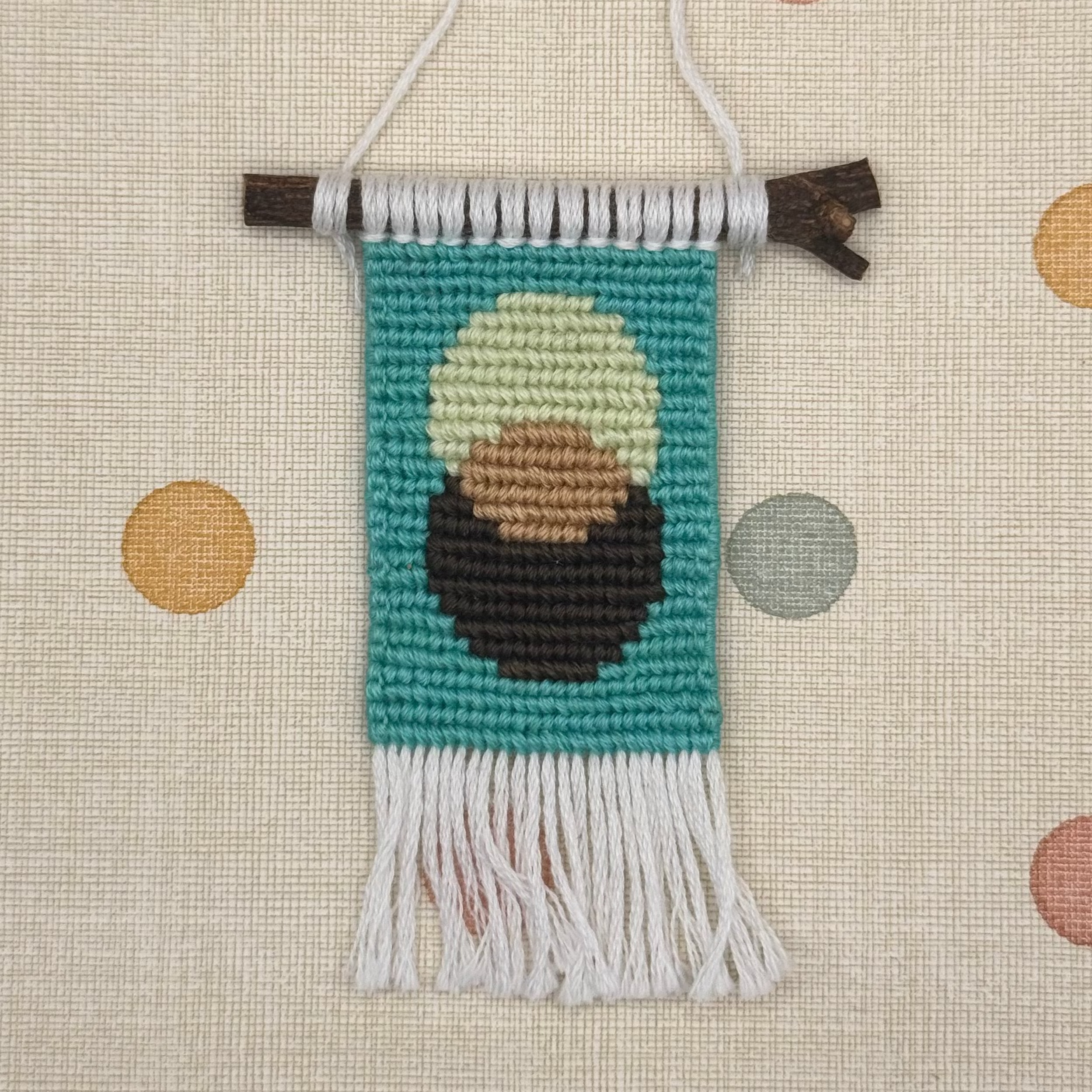 Textile art piece with a portrait of a person with a green background on a polka dot fabric background.