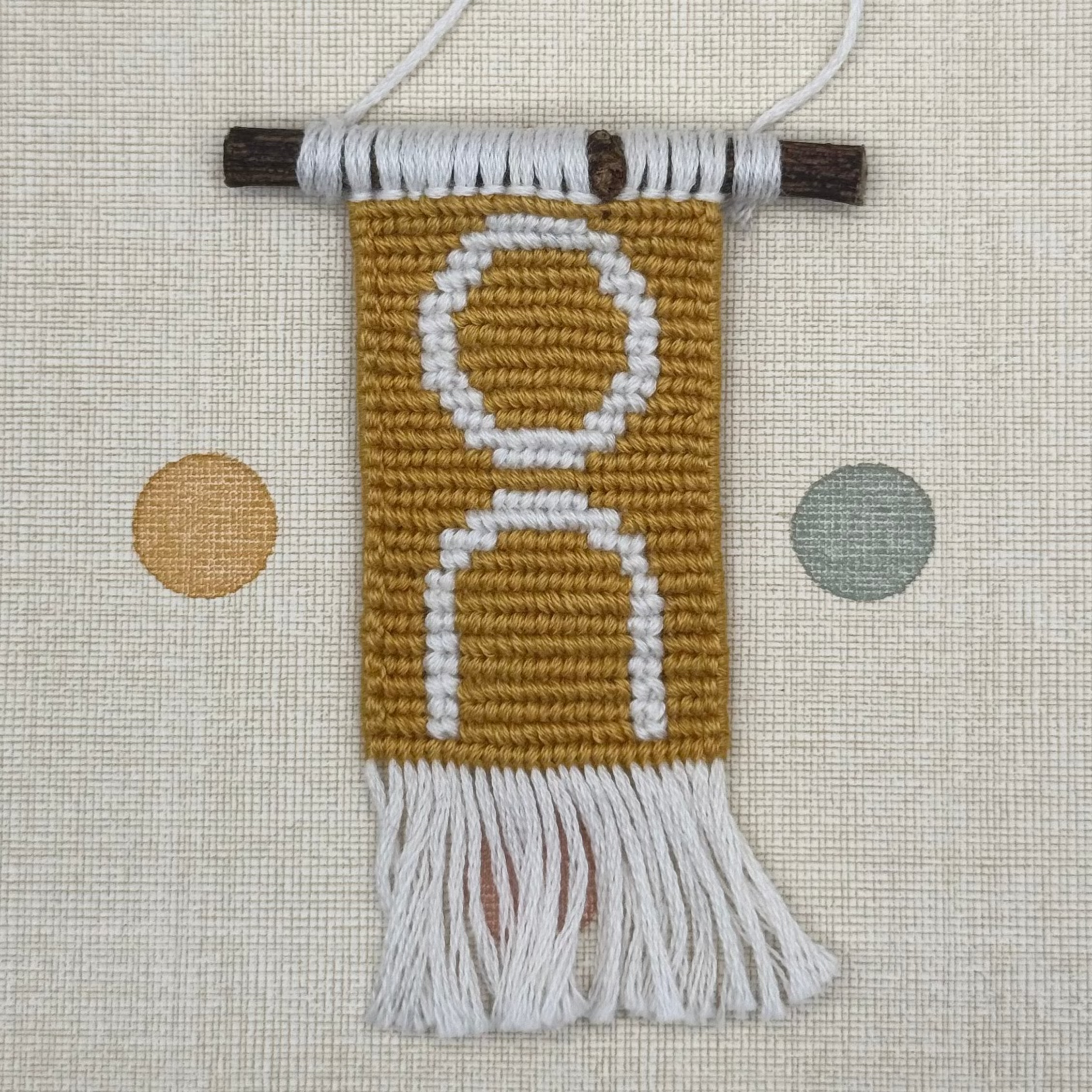 Textile wall hanging with fringe on a polka dot background