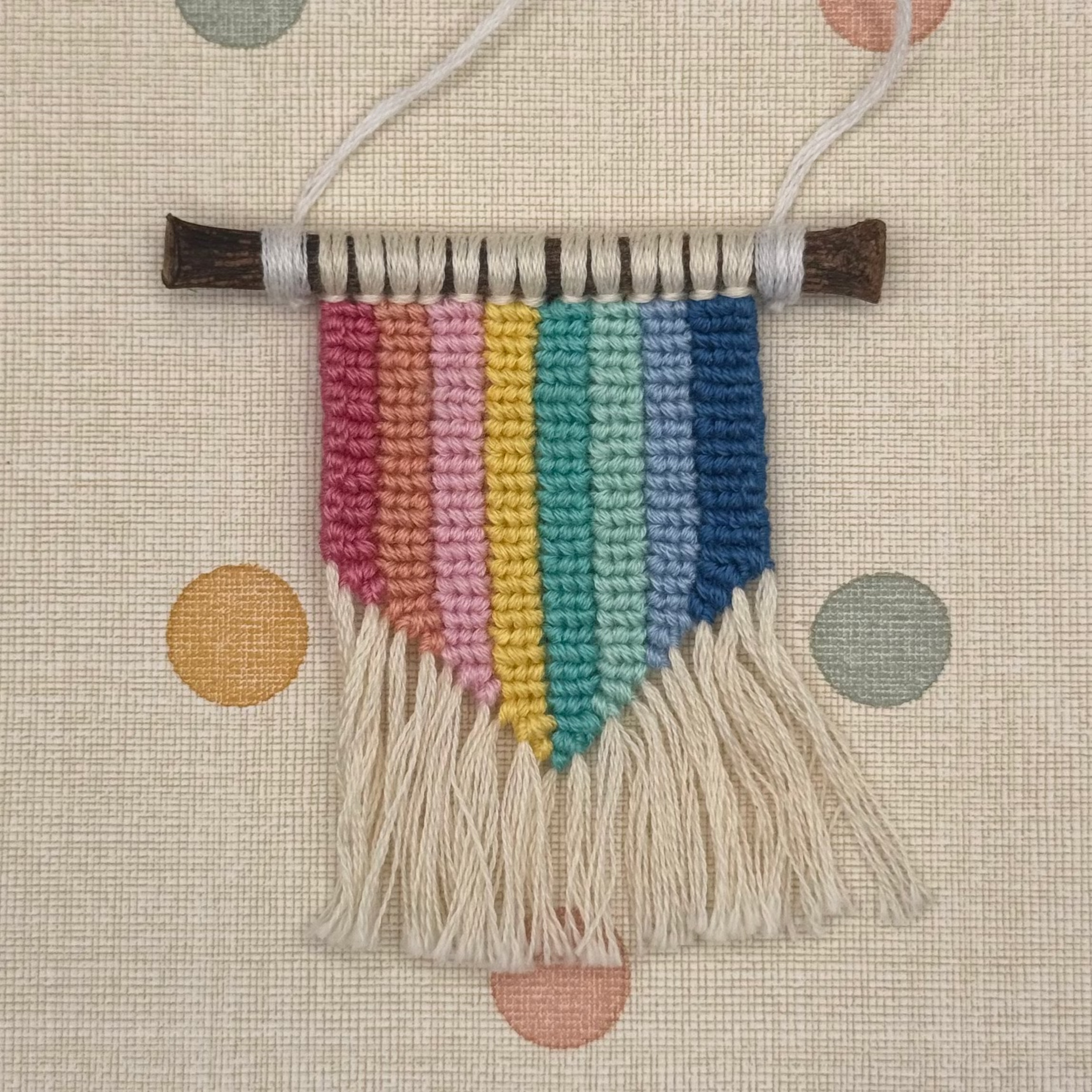 Colorful woven wall hanging on a polka dot background