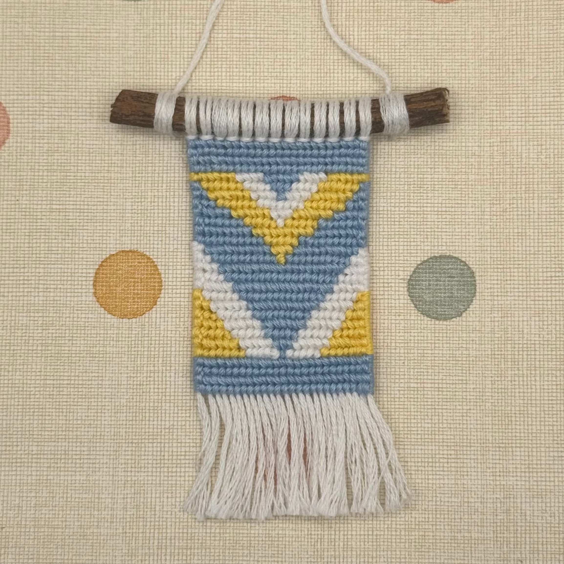 Textile wall hanging with geometric pattern on a polka dot background