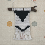 Textile art piece with black and white pattern on a polka dot background