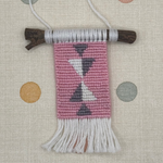 Small woven wall hanging with geometric pattern on a polka dot background