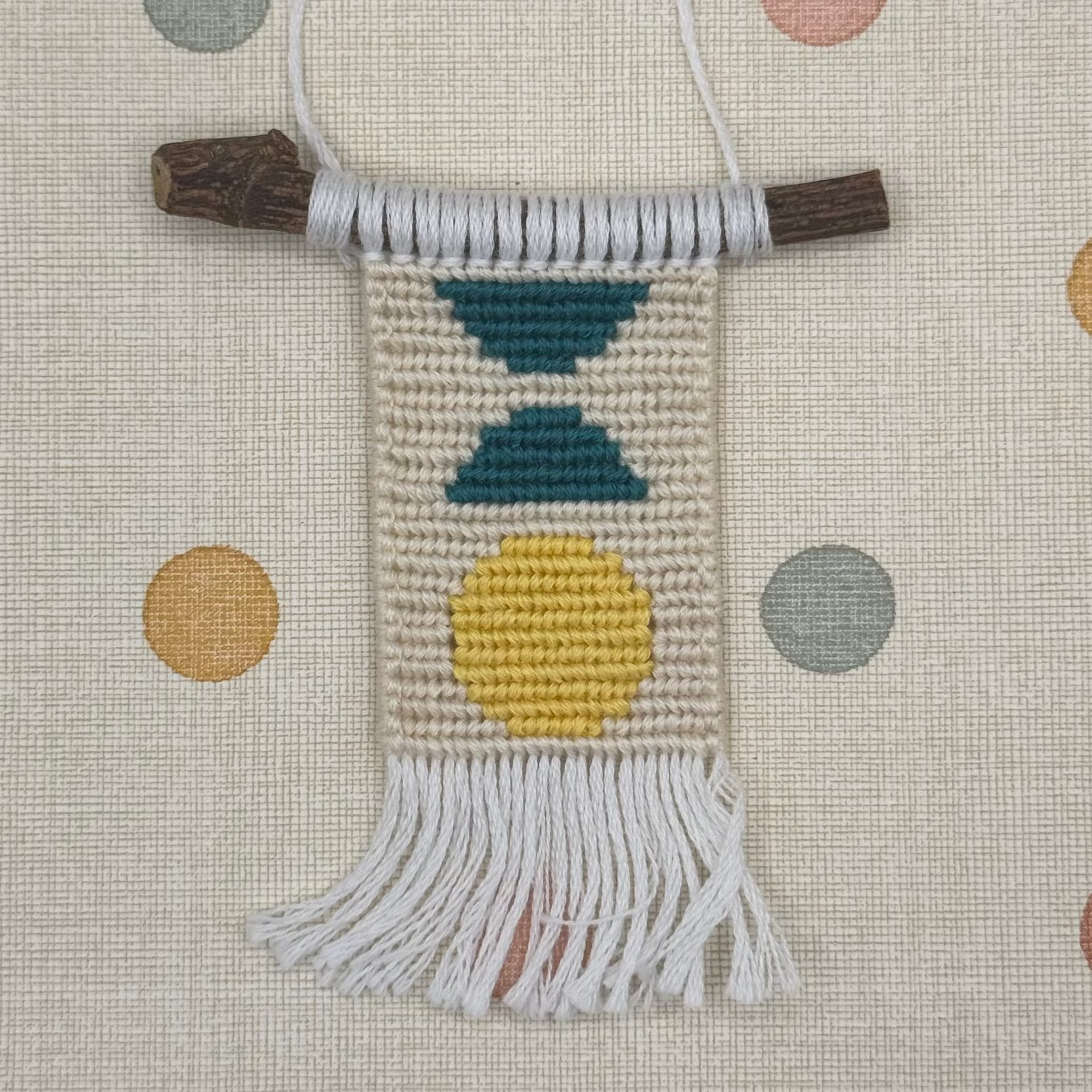 Textile wall hanging with colorful patterns on a polka dot background