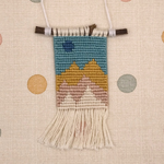 Handmade woven wall hanging with a landscape design on a polka dot background