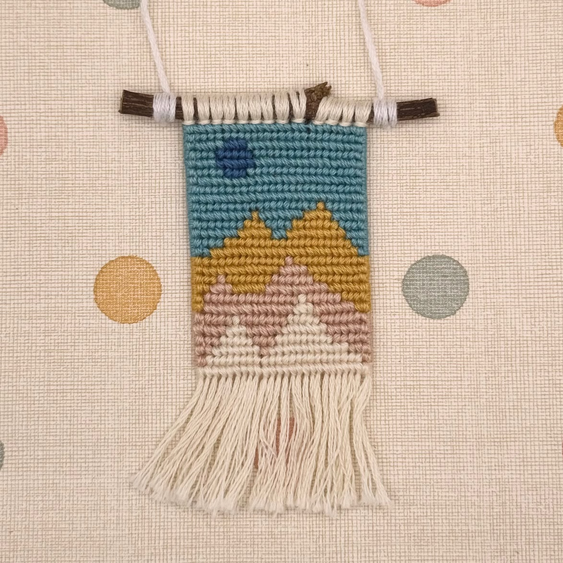 Handmade woven wall hanging with a landscape design on a polka dot background