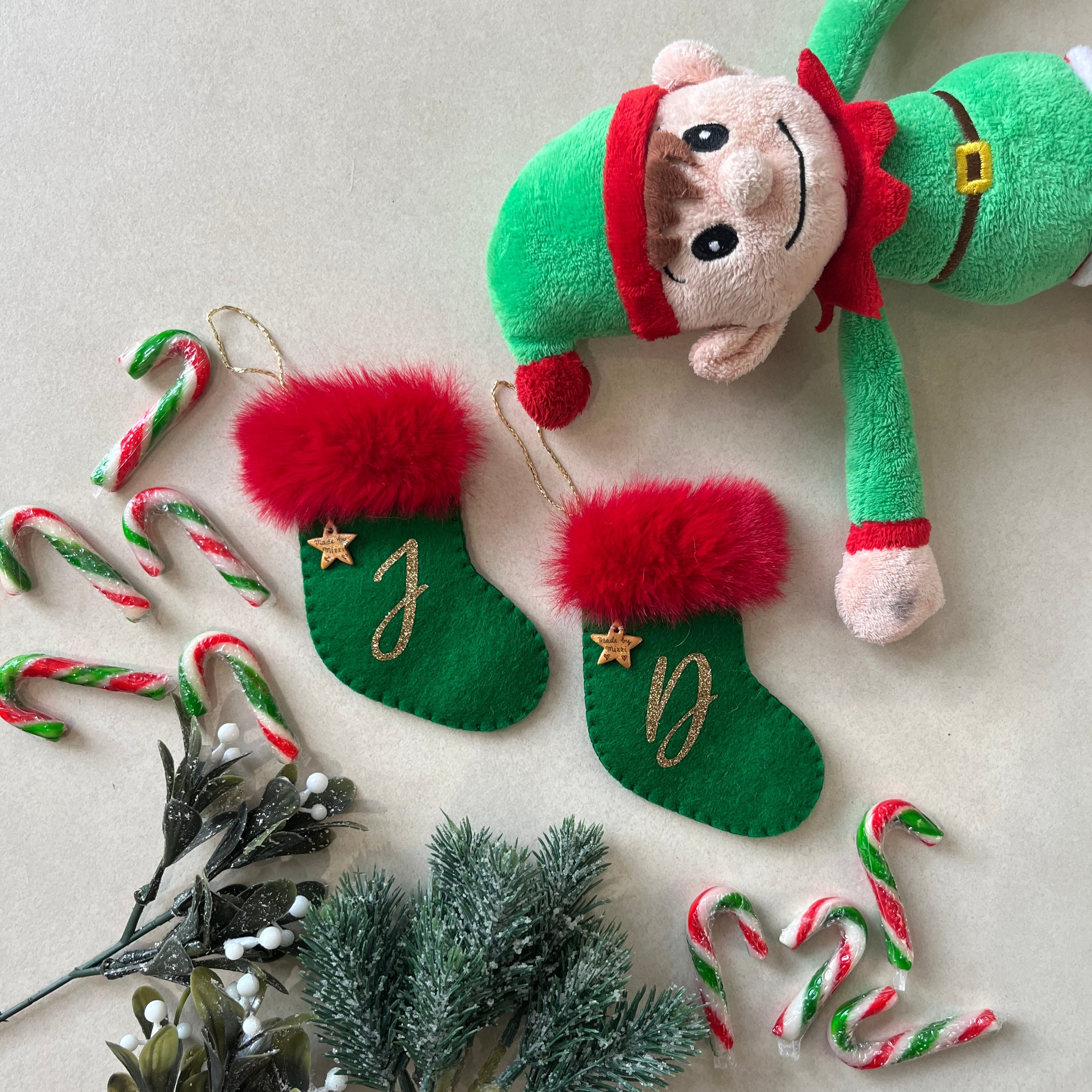 Christmas-themed items including a plush elf, stockings, candy canes, and mistletoe on a light background.