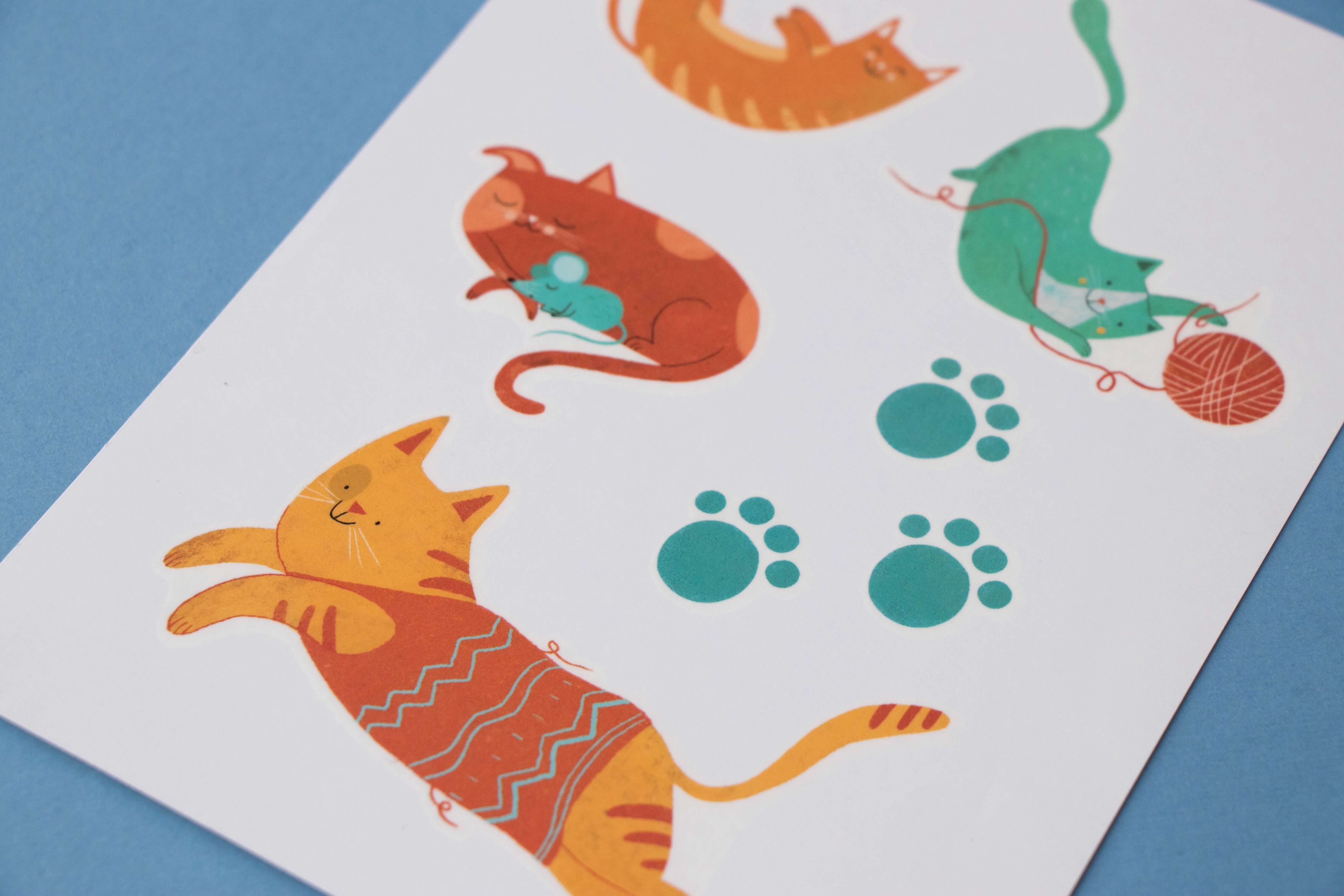 Londji colorful cat tattoos on a white sheet with blue background
