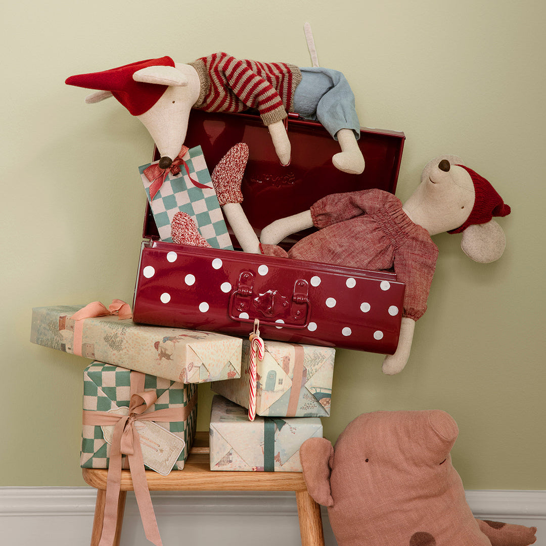 Maileg mice and stack of gift boxes with stuffed toys on a chair against a light green wall