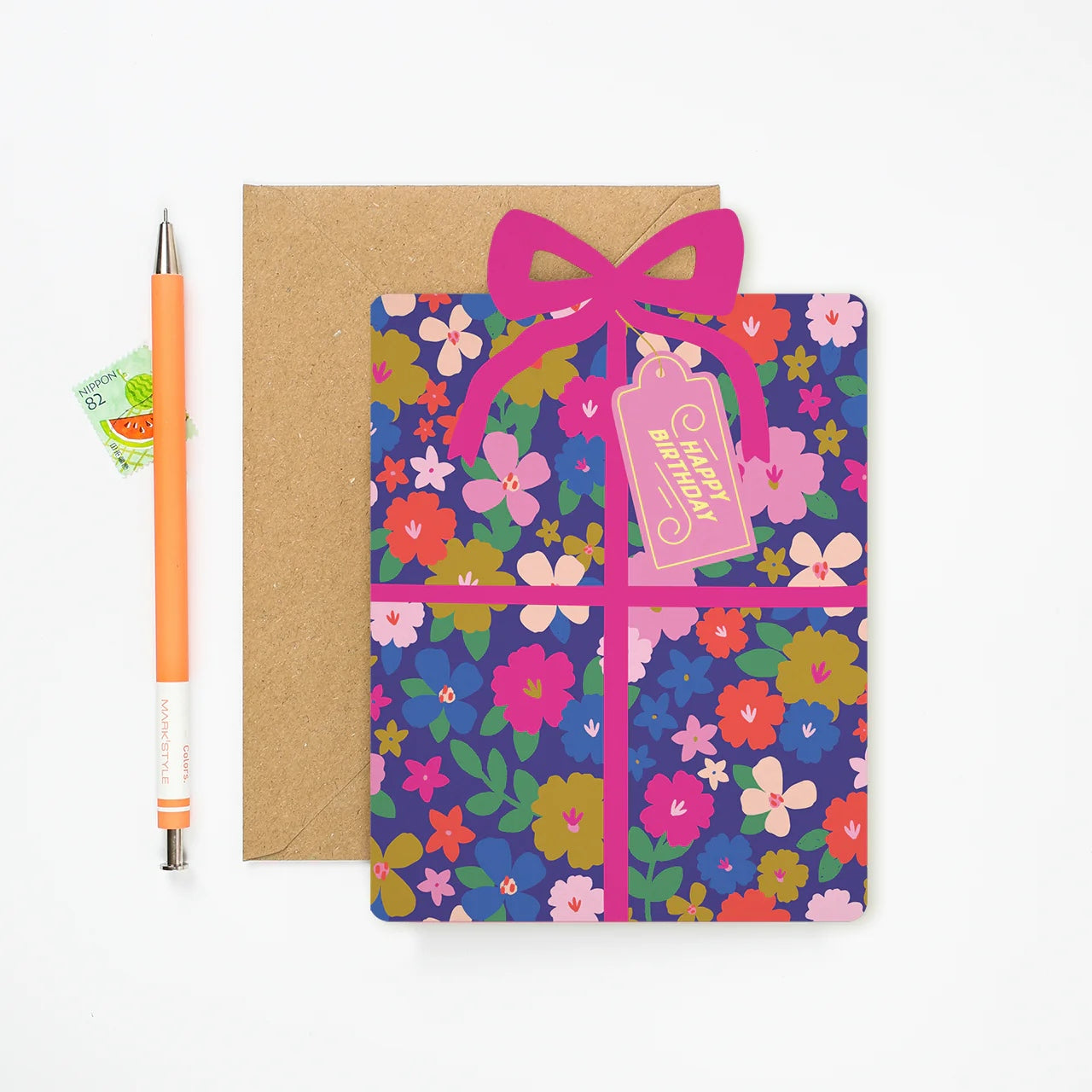 Mifkins floral card with a pink ribbon and 'Happy Birthday' tag, next to an orange pen on a white background.