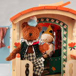 Moulin Roty teddy bear with a hat inside a wooden playhouse