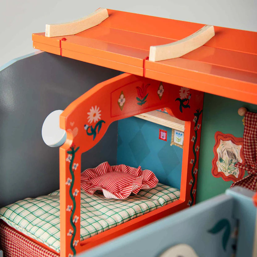 Moulin Roty children's caravan with orange roof and decorative elements on a gray background
