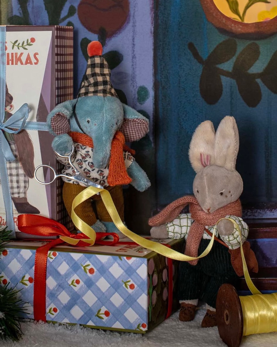 Two toy animals, an elephant and a rabbit, sitting on a decorative setup with a gift box and ribbon.