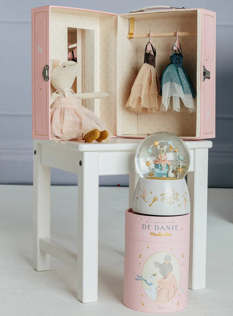 Pink toy wardrobe with dolls and a snow globe on a white surface