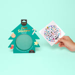 Tree-shaped OMY face sticker set with a hand holding a sheet of stickers against a light green background