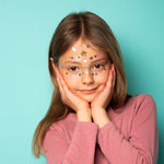 Young girl with OMY face stickers against a light blue background