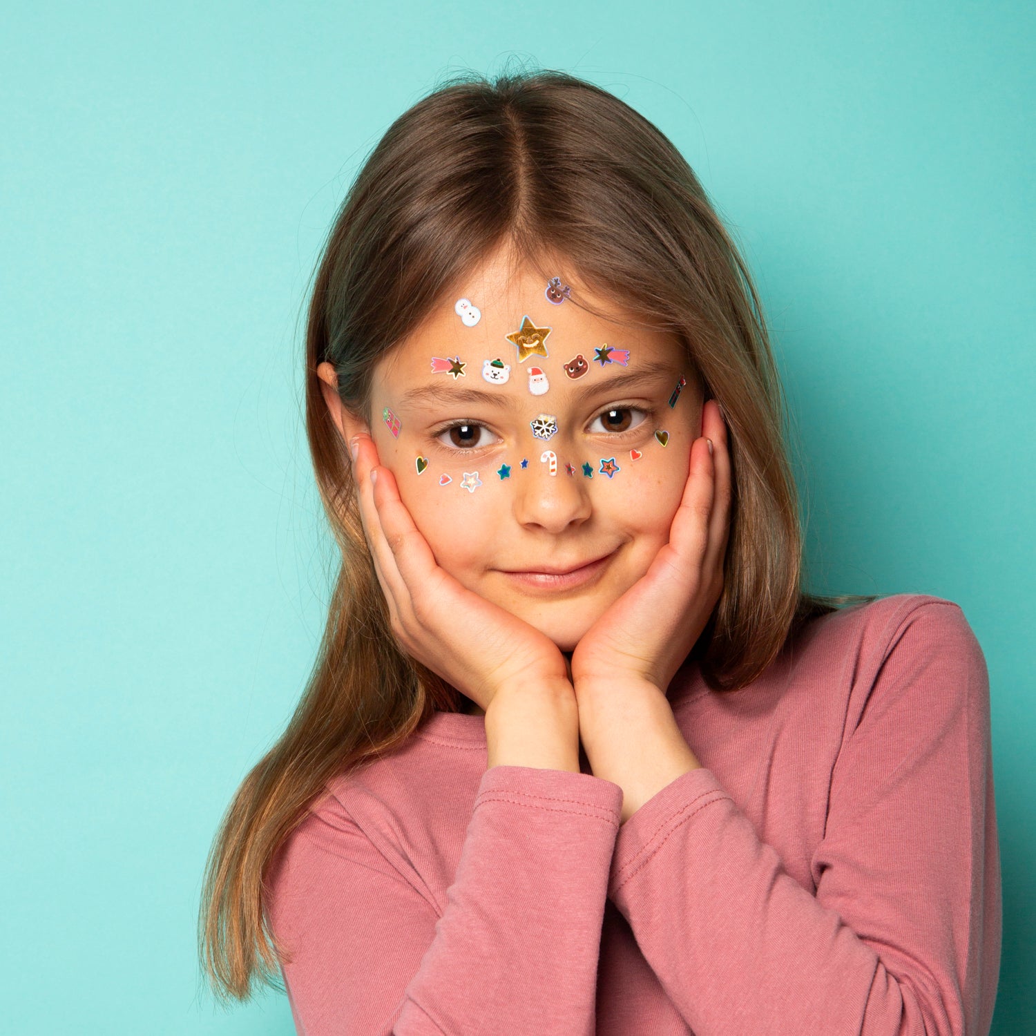 Young girl with OMY face stickers against a light blue background