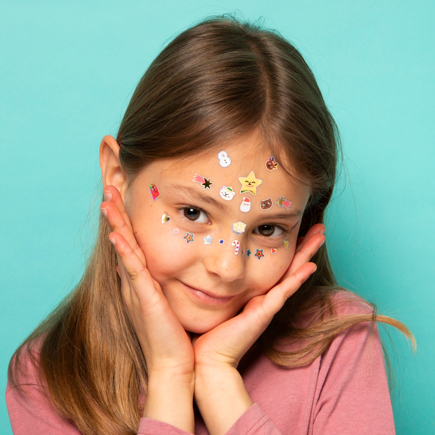 Young girl with OMY face stickers on her face against a light blue background