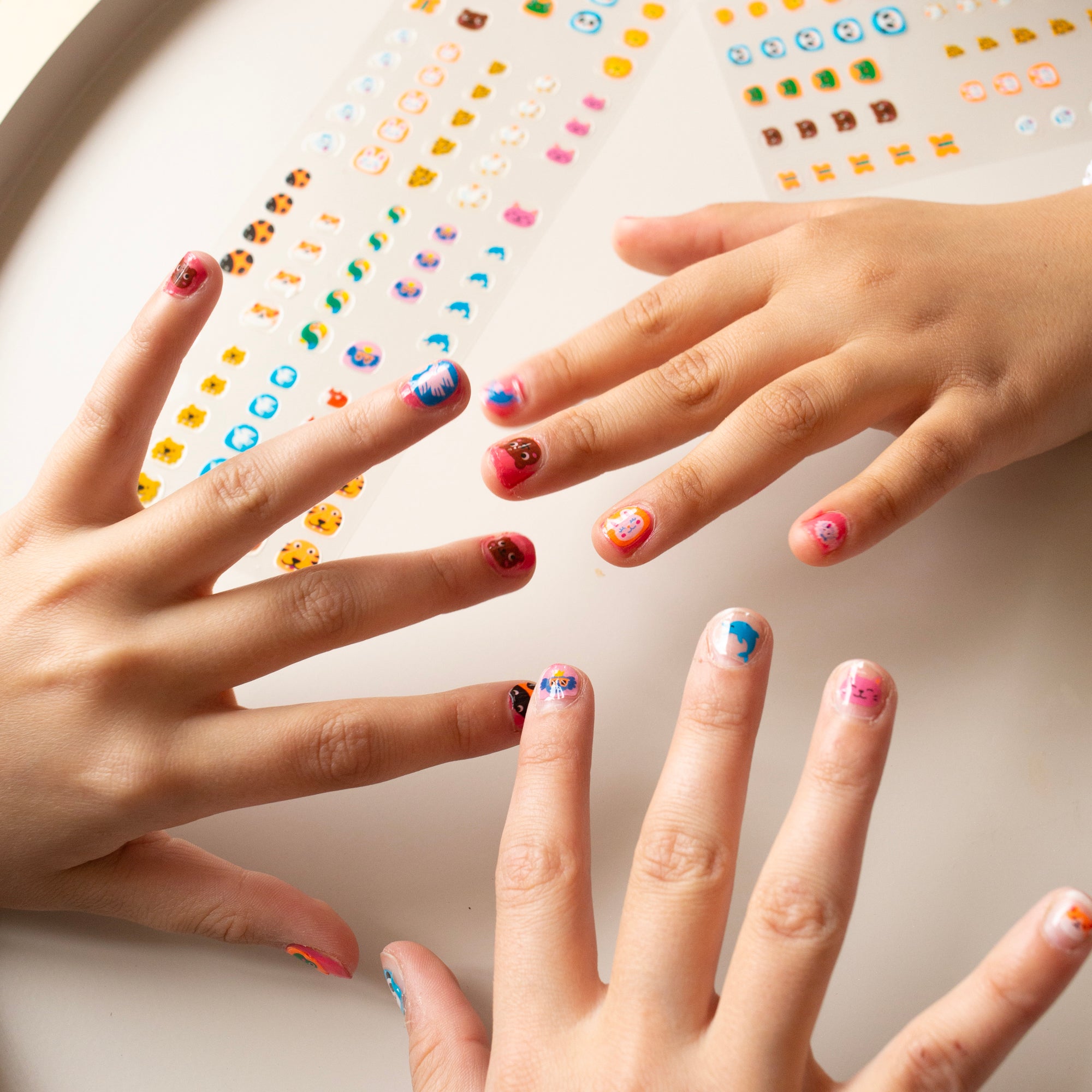 Close-up of hands with colorful OMY nail stickers against a light background