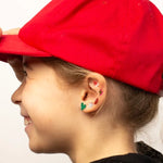 Person wearing a red cap and colorful OMY earrings on a plain background
