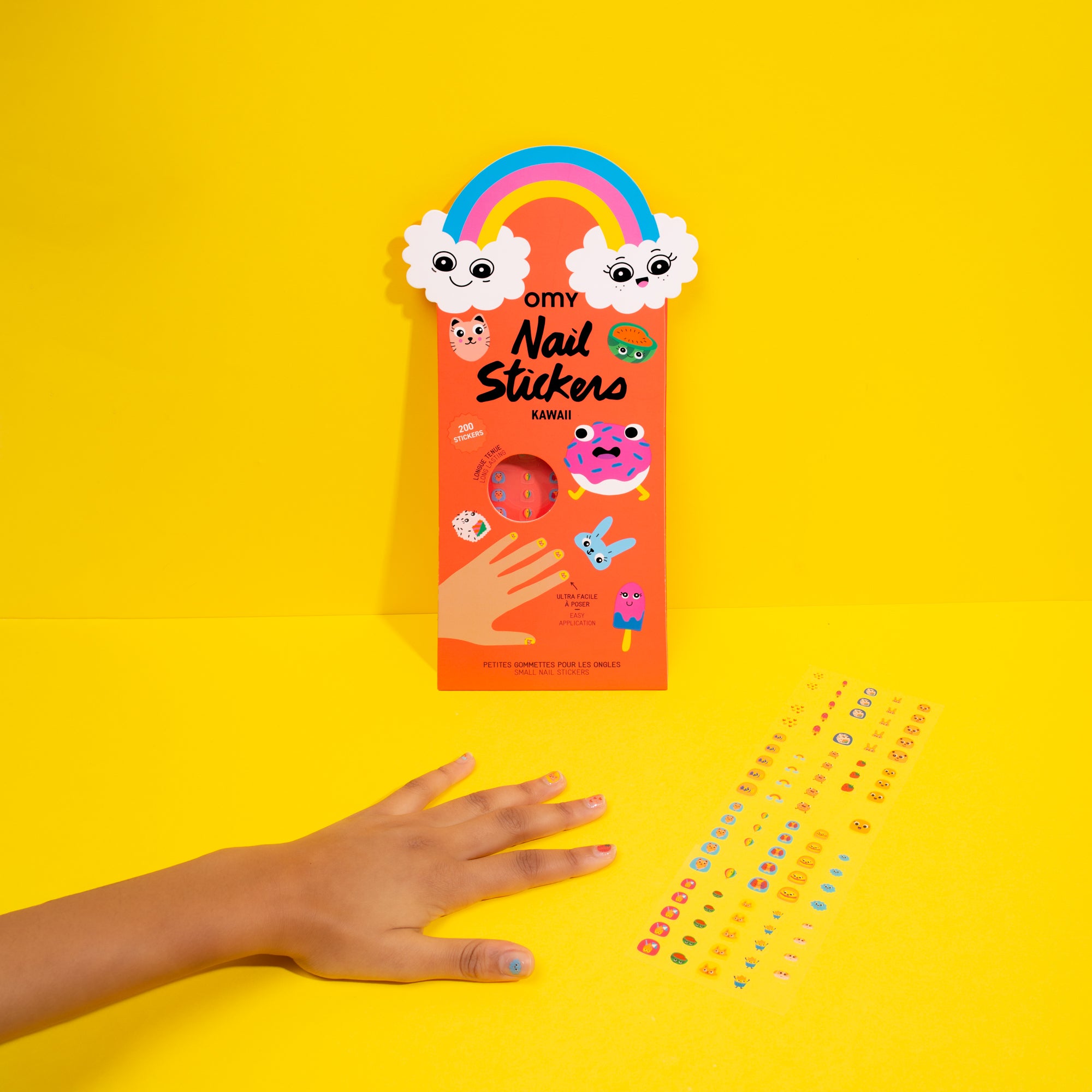 Pack of OMY nail stickers with a hand and additional stickers on a yellow background