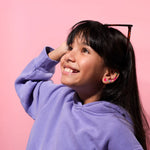 Young girl wearing a OMY earrings against a pink background